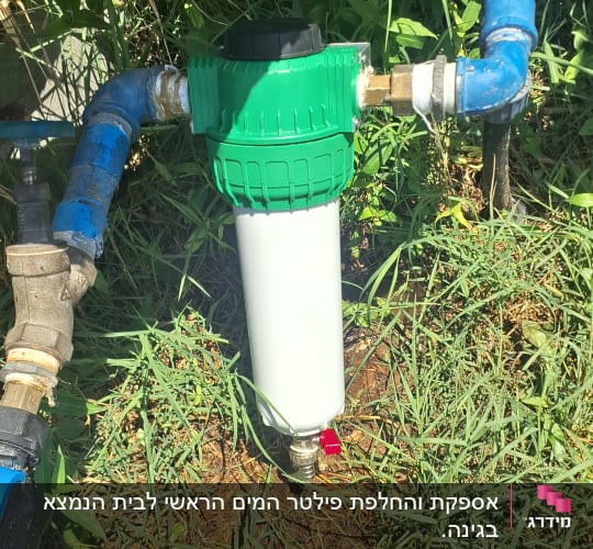מסנן מים ירוק ולבן מחובר לצינורות כחולים